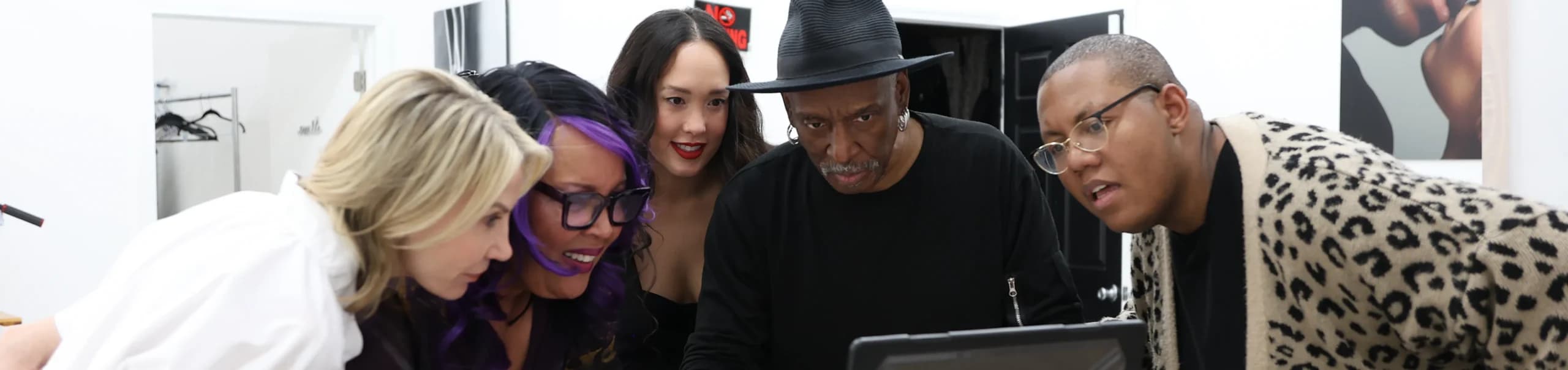 A small group gathered around a laptop backstage at an LVFC event
