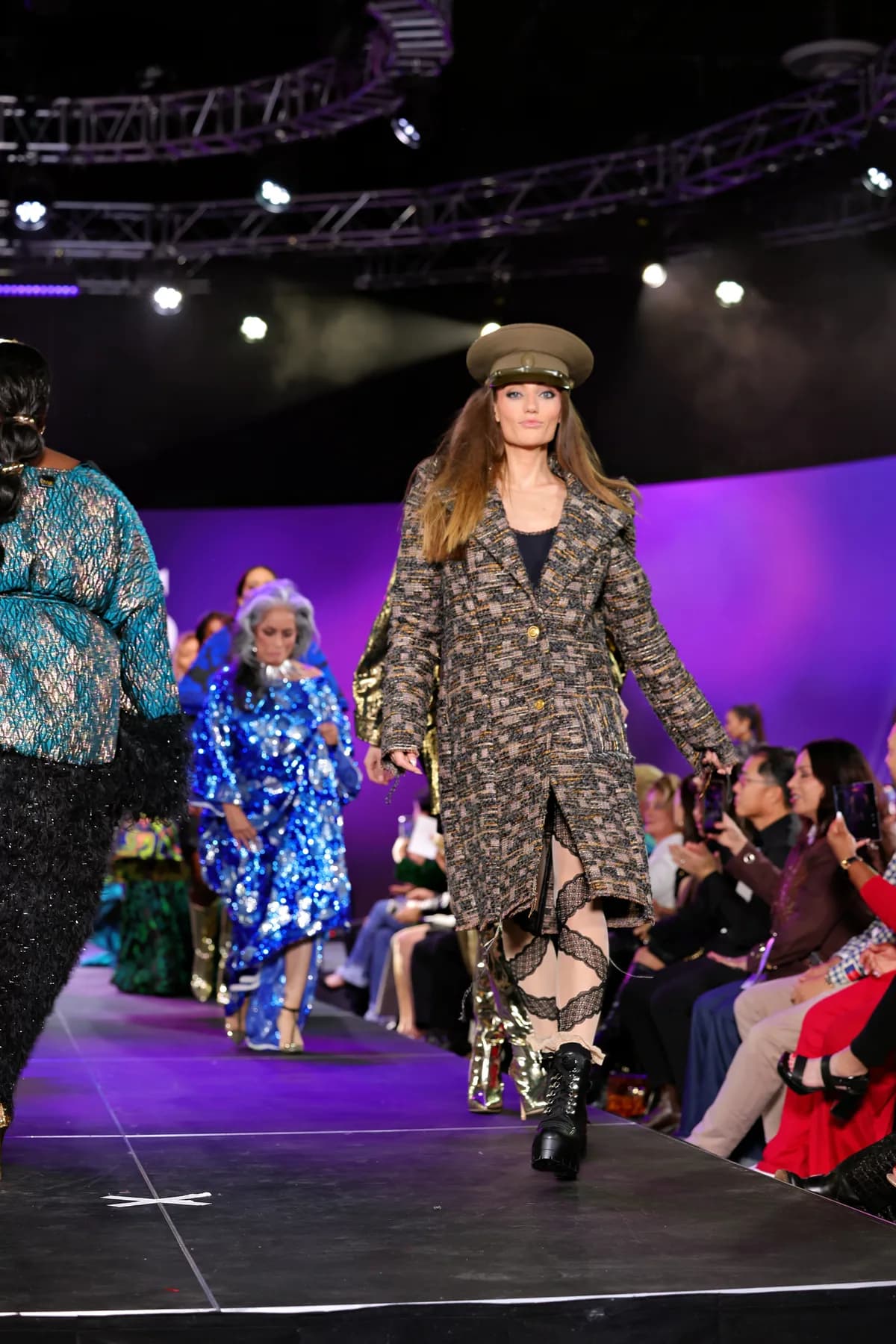 A model presents a designer's look on the runway at Vegas Fashion Week®, the front row beside the stage