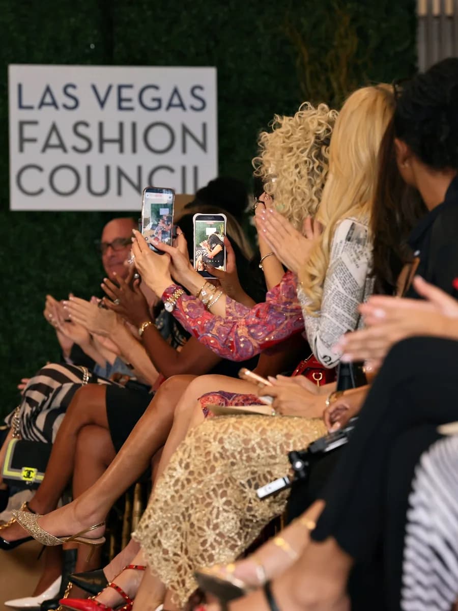 Guests in the front row film the runway at Eco Couture Vegas 2026, the Las Vegas Fashion Council's sign behind them