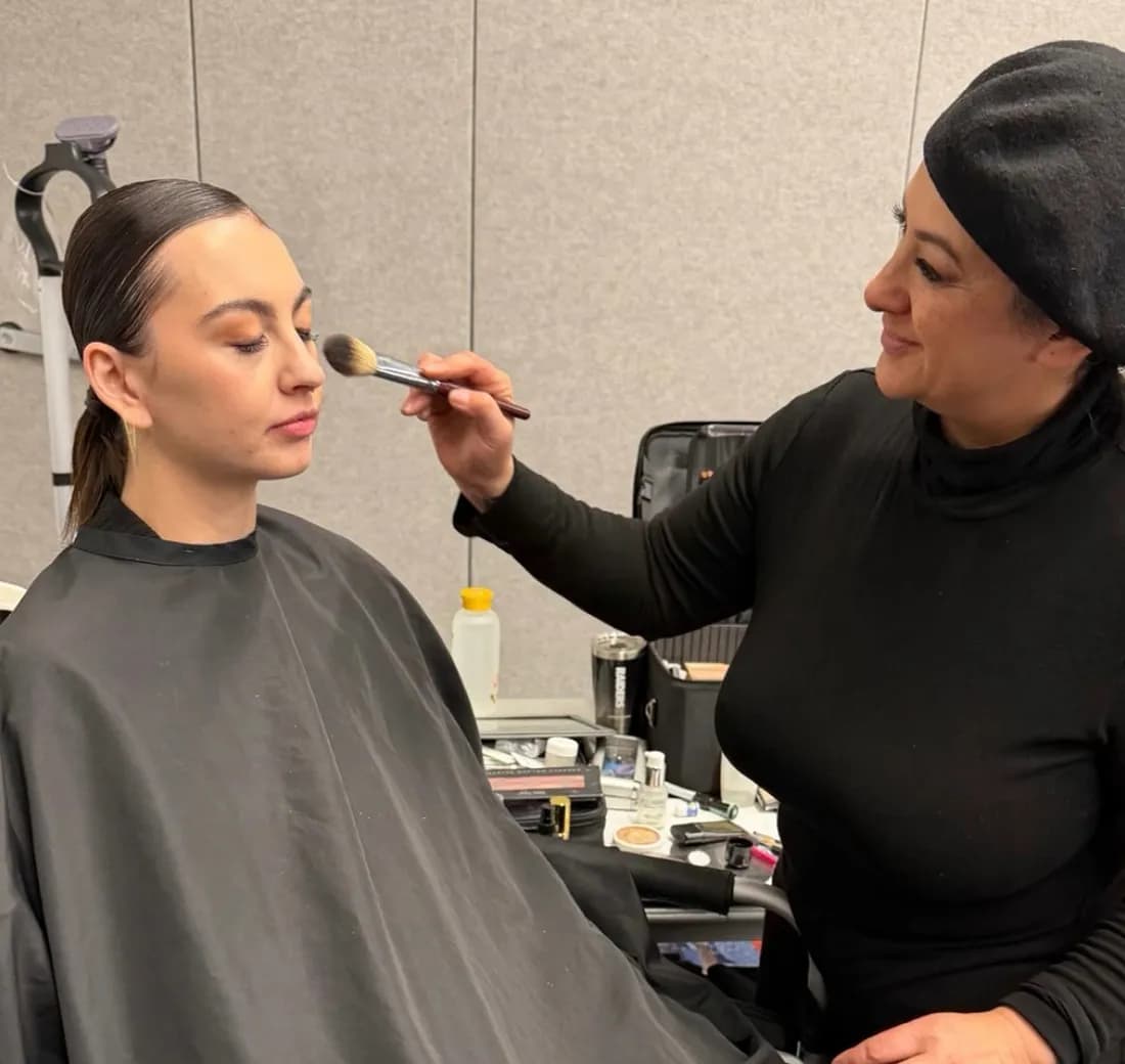 A makeup artist preparing a model backstage at a Vegas Fashion Week® show