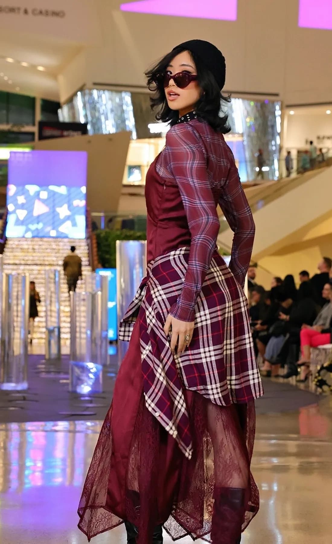 A runway presentation in a shopping-center atrium, with guests seated along the runway